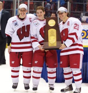 Bobbi-Jo Slusar, Sara Bauer, and Phoebe Monteleone pose with the NCAA trophy.